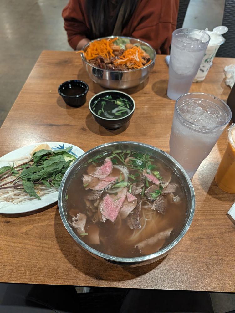 A big bowl of pho and side dishes on a restaurant table